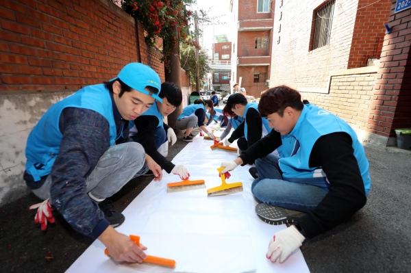지난 15일 서울 마포구에서 대우건설 직원들이 노후주택에 도배할 벽지에 풀을 바르고 있다.